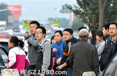 沒擠上的乘客翹首企盼下一輛公交車的到來。