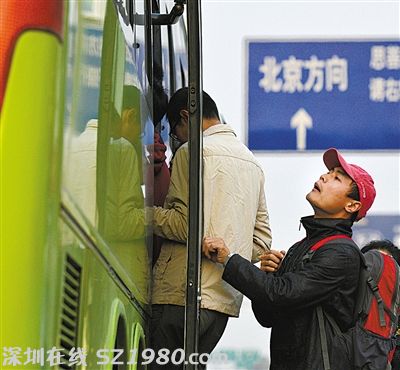 一名乘客在車門口往車?yán)飶埻?，看是否還有空位能擠進(jìn)去。