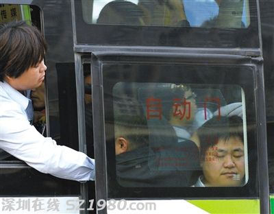 售票員用手將門口的乘客往里推，以便車門能順利關(guān)上。